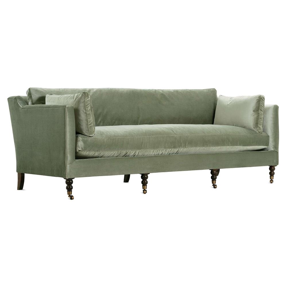 green velvet sofa with bolster pillows and turned wood legs with brass casters