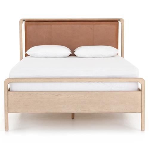 A midcentury modern bed with a light brown oak wood frame and a leather headboard