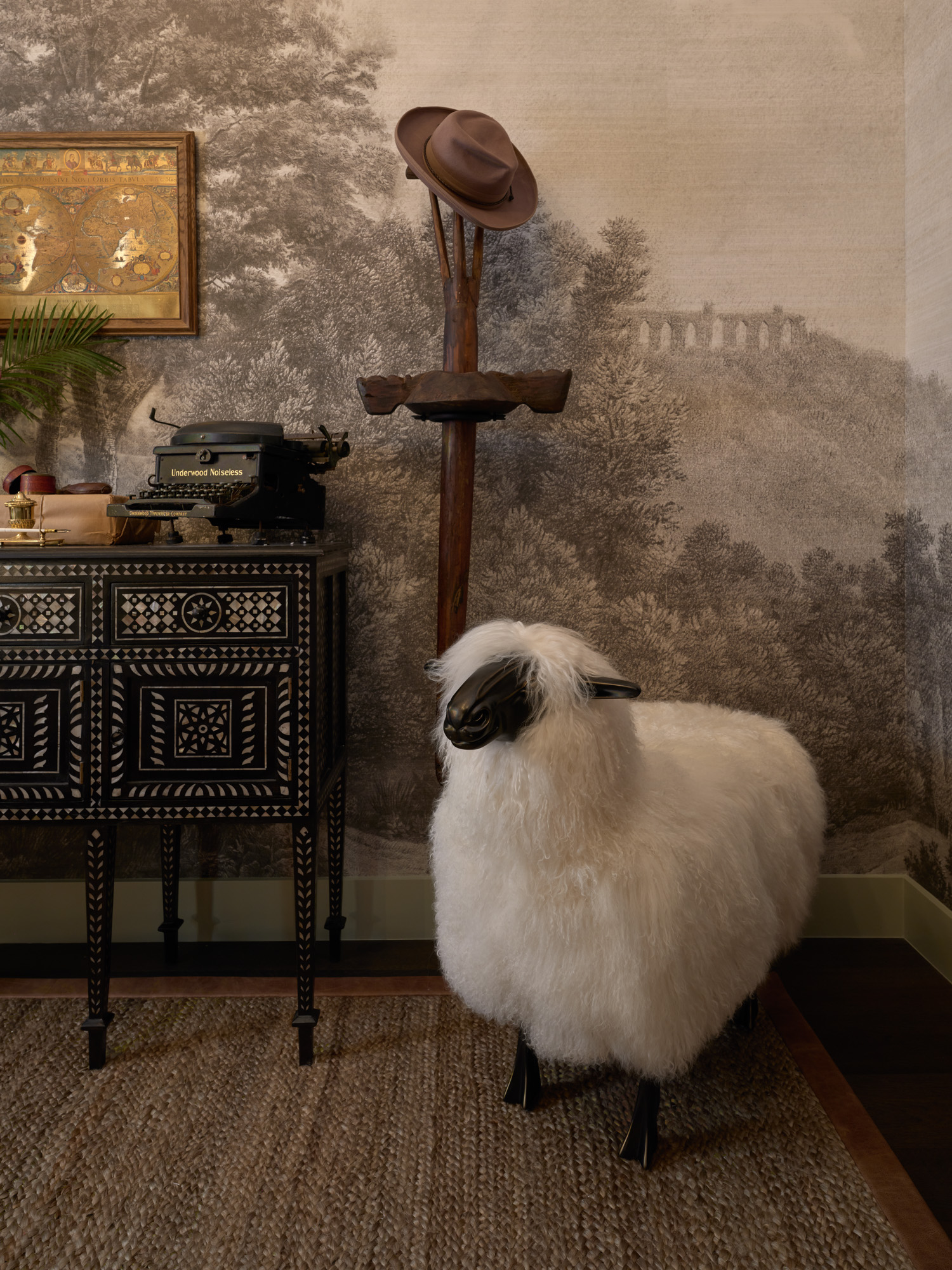 A white sheep statue stands in the corner of a cozy primary bedroom with a jute rug underneath its feet