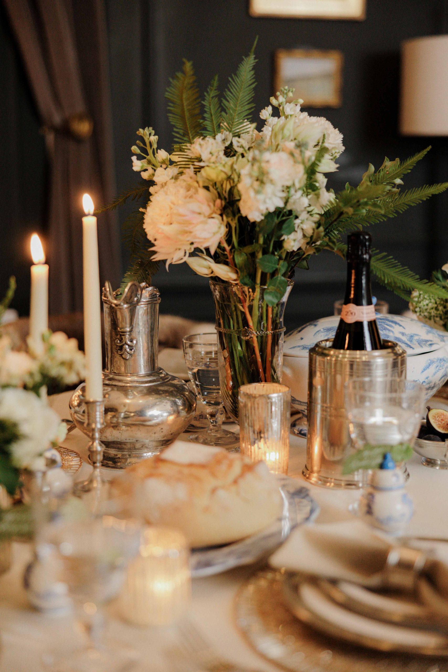 holiday tabletop with tapere candles, flowers, and white and silver dishware