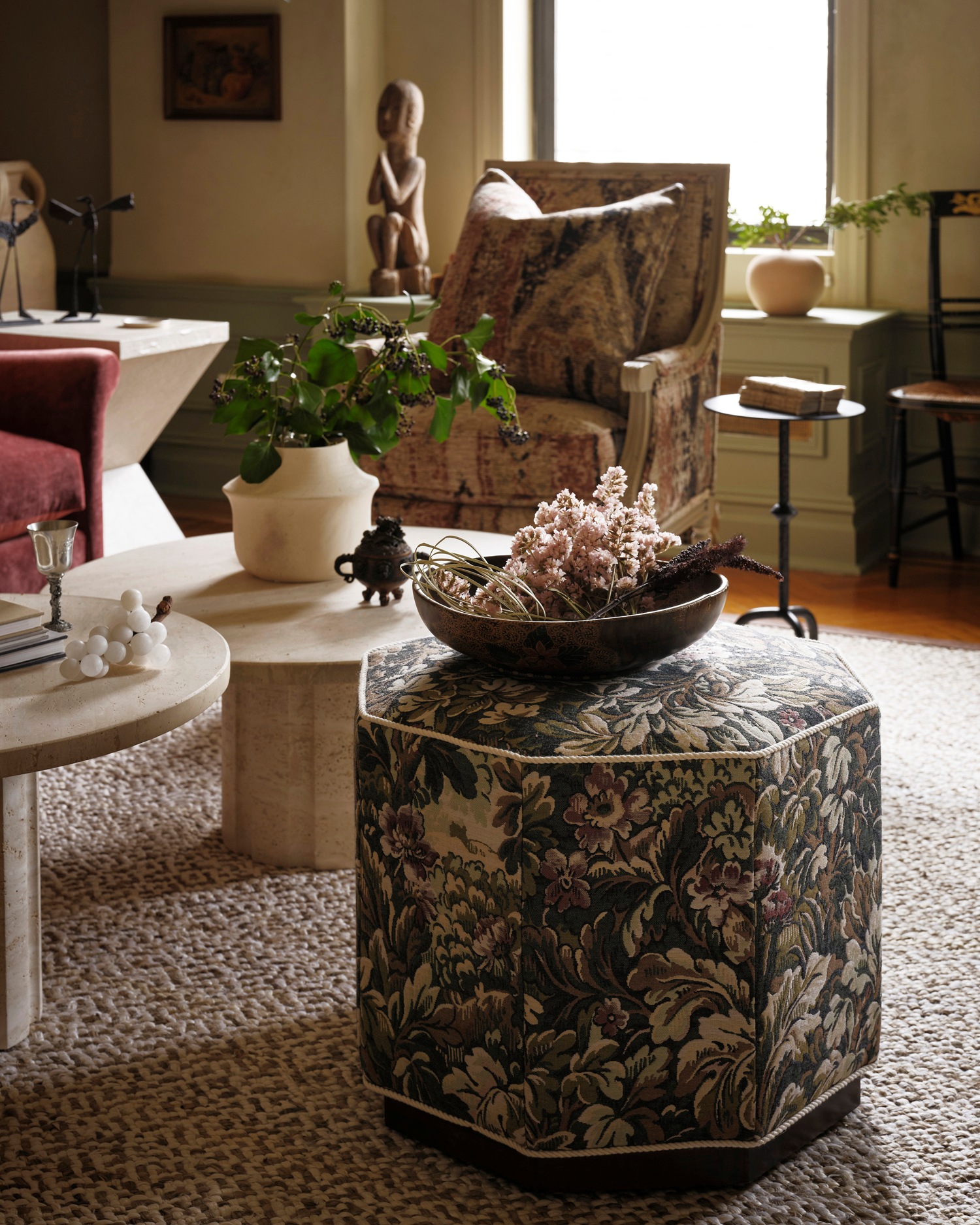 A tapestry fabric ottoman sits next to travrtine marble coffee tables in Kathy Kuo's New York living room