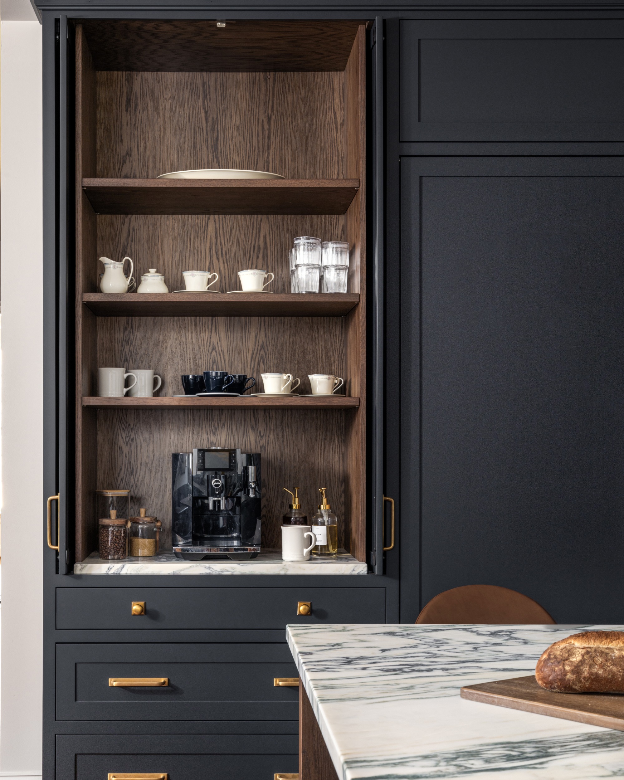 A custom coffee bar in a ktichen with pocket doors and navy blue painted cabinets